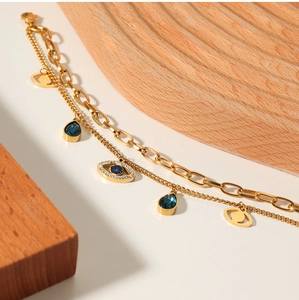 Close-up of golden double-layer evil eye bracelet with blue glass charms on wood decor