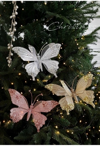 Dettaglio di farfalle natalizie in mesh con glitter e perle su un albero illuminato