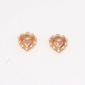 Macro shot of gold heart earrings with micro-set zircon and faceted pink-orange gemstone