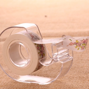 Transparent desktop tape cutter dispenser with floral washi tape on linen background
