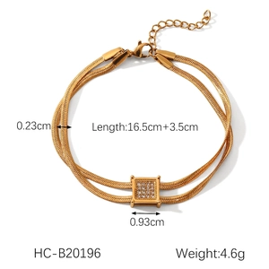 Macro view of gold double-layer snake chain bracelet with crystal square pendant
