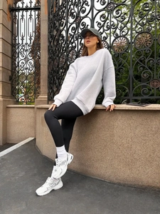 Detail of grey drop-shoulder sweatshirt and black ribbed leggings in casual street style