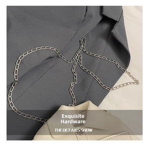 Close-up of shiny silver metal chain link hardware and cream white leather bag
