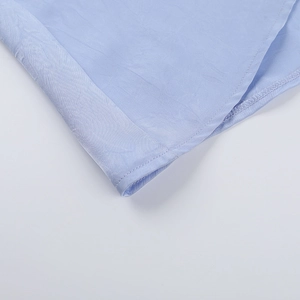 Detailed close-up of light blue satin fabric with fine stitching and smooth texture