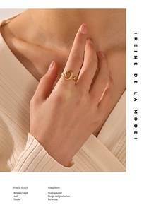 Close-up of minimalist gold-plated oval open ring worn on a finger with knitwear background