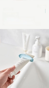 Macro shot showing the narrow opening of the light blue manual toothpaste squeezer tool