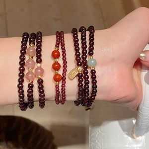 Detail of layered garnet and strawberry crystal beads with a golden Fu pendant