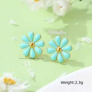 Macro detail of 1.2cm blue daisy stud earrings with gold center on floral background