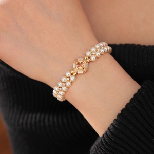 Détail d'un bracelet de perles à double rangée avec fermoir doré et pierre précieuse champagne
