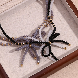 Détail d'un collier de perles multicouche avec pendentif nœud noir et blanc sur plateau