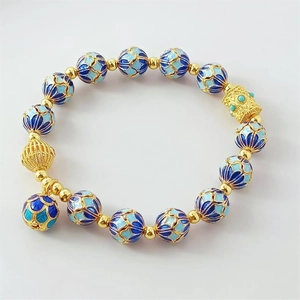 Detailed macro view of 18K gold-plated cloisonne beads with blue enamel floral patterns