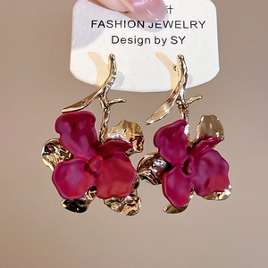 Macro detail of dark red matte flower earrings with golden textured metal branches