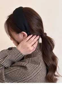 Elegant wide black fabric headband on female model with vintage brown checked wool coat