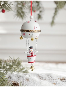 Detail of Christmas snowman in hot air balloon ornament with golden bell and pine branches