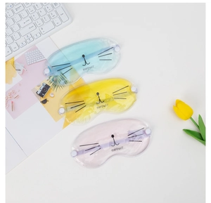 Three cat-themed cooling eye masks in blue, yellow, and purple on a white desk setup