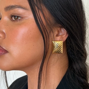Golden rectangular striped titanium steel stud earrings worn by a model on a side profile