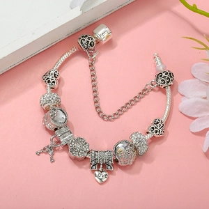 Macro detail of silver-plated snake chain bracelet with heart charms and love pendant