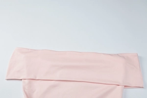 Detail of pink off-shoulder dress featuring smooth fabric and professional stitching