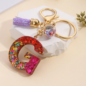 Detail of resin letter G keychain with colorful glitter sequins and purple tassel