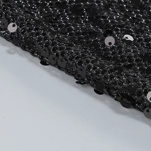 Close-up of black sequin fabric detail with mesh texture on elegant evening dress