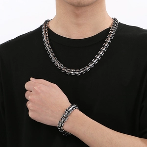 Detail of dark metallic dragon scale chain necklace and bracelet on male model