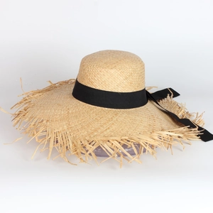 French straw sun hat with black ribbon and frayed edges on white background