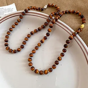 Vintage tiger eye beaded necklace with metallic spacers on a rustic ceramic plate