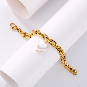 Detailaufnahme des goldfarbenen Gliederkettenarmbands mit weißem Herzanhänger aus Muschel