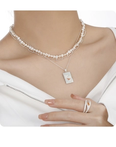 Detail of layered S925 silver pearl necklace with rectangular pendant and matching ring
