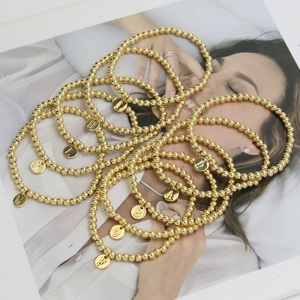 Detailed shot of golden beaded bracelets with engraved round alphabet letter charms