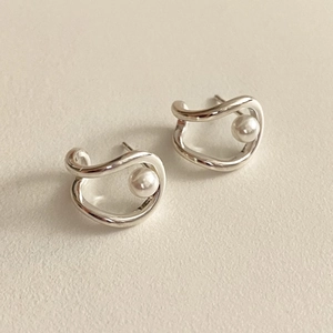 Macro shot of 925 silver irregular curved earrings with embedded white pearls
