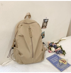 Close-up of beige nylon backpack with adjustable drawstring side detail in casual setting