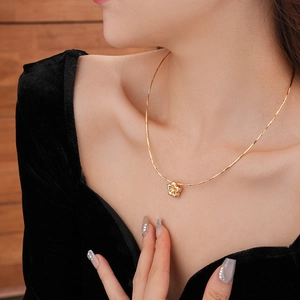 Dettaglio di una collana a fiore dorato con zircone centrale e catena a serpente su velluto