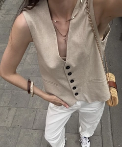 Detail of beige linen blend vest featuring V-neckline and single-breasted black buttons