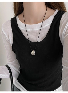 Close-up of minimalist silver teardrop pendant with black cord on a female model