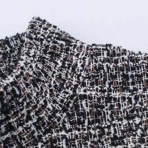 Détail du col montrant le tissu en tweed texturé noir, blanc et marron