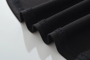 Détail du tissu en maille noire montrant l'ourlet sirène surjeté et la texture ondulée