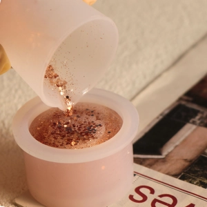 Detailaufnahme beim Gießen von Harz mit Roségold-Pailletten in einen Silikon-Messbecher