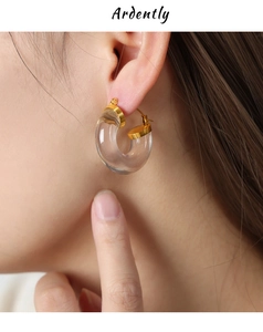 Close-up of a model wearing a clear C-shaped resin earring with gold metal accents