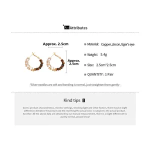 Macro view of 18k gold plated hoop earrings with zircon and tiger's eye stones