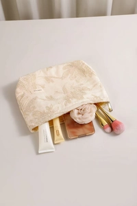 Détail de la trousse de maquillage en lin crème avec broderie florale et grande capacité