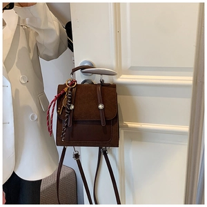 Detalle de mochila vintage marrón oscuro colgada con un elegante accesorio trenzado