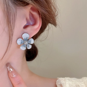 Close-up of a blue flower stud earring with ice-cracked texture on a female model