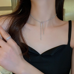 Detail of silver bow necklace with shimmering cubic zirconia and long tassels