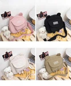 Detail view of mini canvas crossbody bags in four colors with cute bear plush pendants