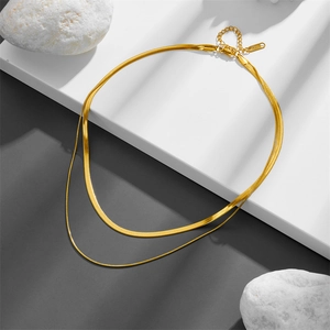 Double-layered golden herringbone snake chain necklace on white minimalist display stand