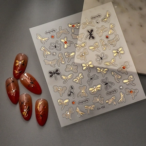 3D metallic dragonfly nail stickers with gold frame and crystal accents on manicured nails