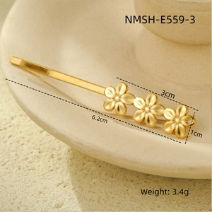 Detailed view of golden flower hair clip with size measurements on ceramic tray