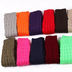 Detail shot of chunky cable-knit leg warmers in various colors on a white background