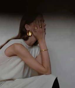 Artistic hammered texture gold earrings and minimalist jewelry set on a female model